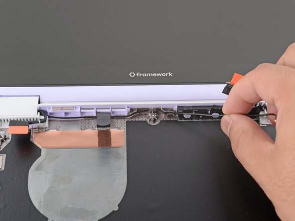 Use your fingers and your Framework Screwdriver to carefully press and guide the black antenna cable back into its channel.