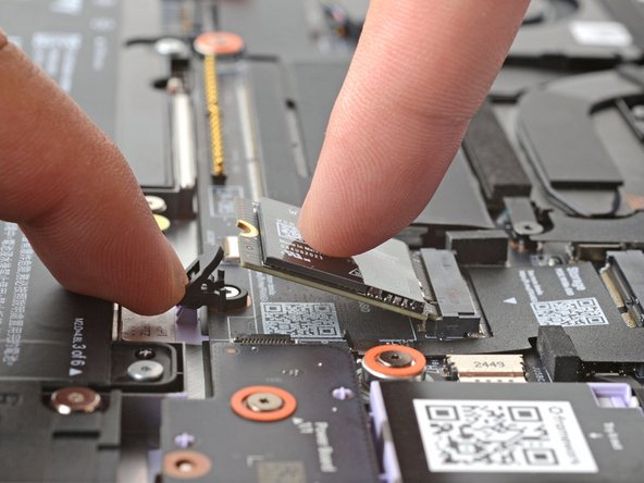 Use your finger to press down on the black SSD latch to keep it open.