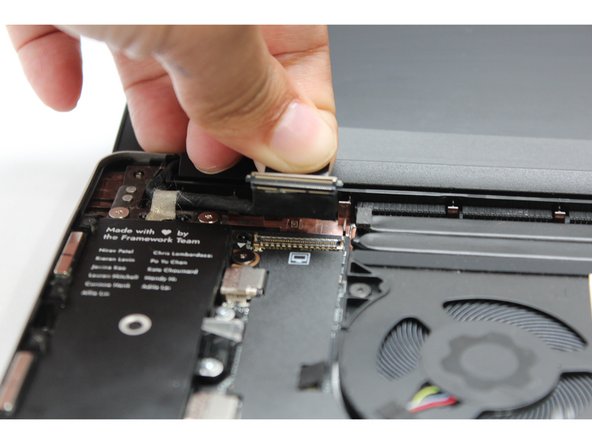 Using your fingers, carefully disconnect the Display cable on the top, left hand side by using the pull tab to pull it upward.