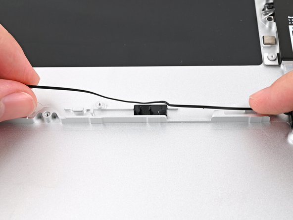 Starting from the right Speaker, press the speaker cable into its metal and plastic clips on the Bottom Cover.