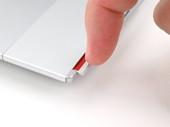 Use your fingernail to pull out the Input Module latch and unlock the Touchpad Spacer next to it.