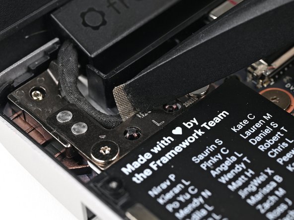 Use the flat end of your Framework Screwdriver to peel off the grounding tape on the left Hinge.