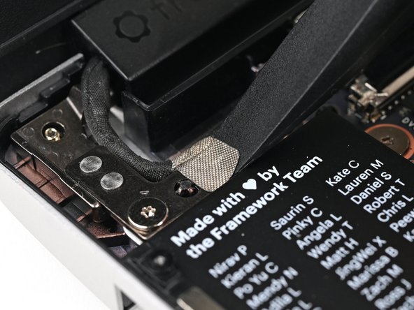 Use the flat end of your Framework Screwdriver to peel off the grounding tape on the left Hinge.