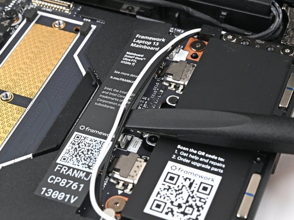 Use your fingers or the flat end of the Framework Screwdriver to lift the two Antenna Cables out of their clips on the Mainboard.