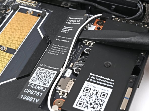 Use your fingers or the flat end of the Framework Screwdriver to lift the two Antenna Cables out of their clips on the Mainboard.