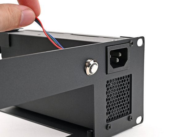 Thread the power button cable through the hole to the left of the power supply plug.