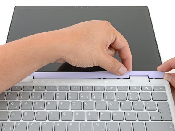 Slide your fingers under the top edge of the Display Cover to release it from the laptop.