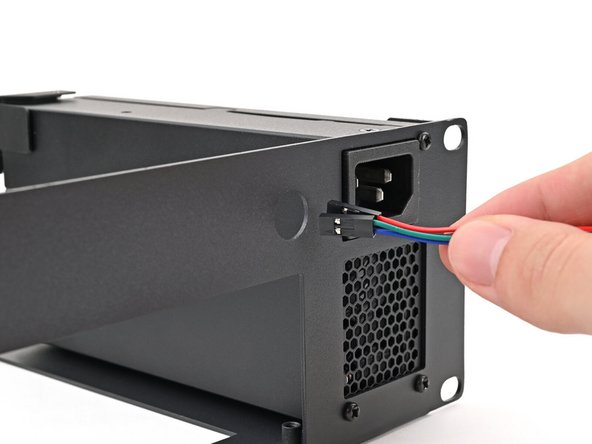 Thread the power button cable through the hole to the left of the power supply plug.