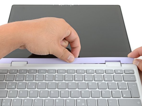 Slide your fingers under the top edge of the Display Cover to release it from the laptop.
