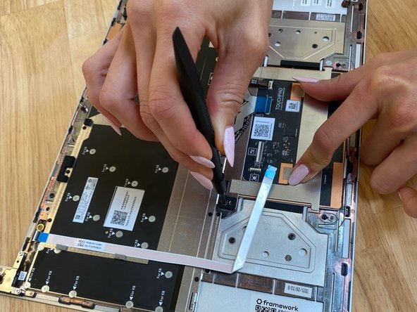 While holding the Touchpad firmly in place to make sure it is aligned,  use the PH0 bit in the  Framework Screwdriver to fasten the top two fasteners into place.