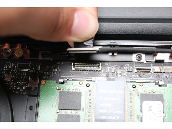 Using your fingers, carefully disconnect the Webcam cable on the top, right hand side by using the black pull tab to pull it directly upward.