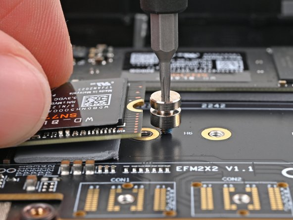 While lightly pressing the SSD into the thermal pad, guide the gap in the SSD screw into the notch on back of the SSD