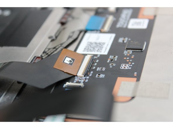 Using the spudger end of the Framework Screwdriver or your fingernail, disconnect the Touchpad Cable by flipping up the black latch up on the connector located on the Touchpad Module.  This will fully disconnect the Input Cover from the Mainboard.