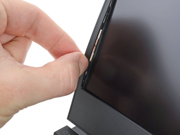 Pull the bezel away from the screen to release the first few magnets.