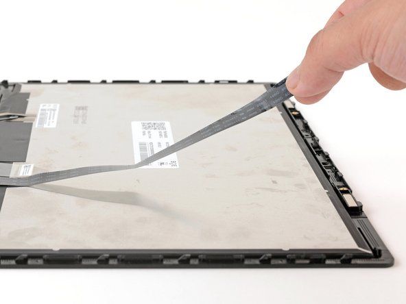 Grab the webcam cable with your fingers and slowly peel it away from the display.