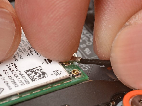 Position the black antenna cable connector over the left Wi-Fi card's coaxial socket.