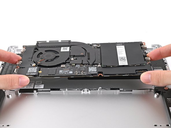 Grab the Mainboard by its edges and place it into the Bottom Cover and onto its alignment pegs.