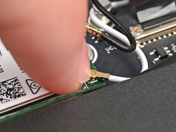 Position the white antenna cable connector over the left Wi-Fi module's coaxial socket.