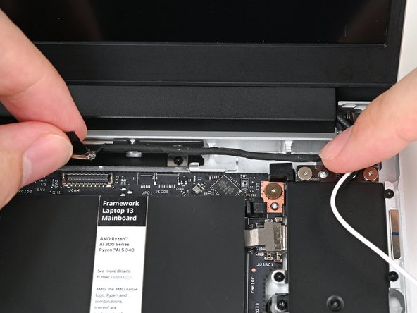 Use your finger to guide the Webcam Cable into its metal pegs on the Bottom Cover.