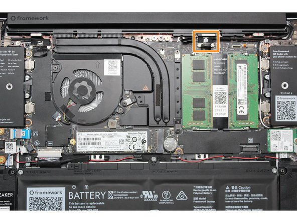 Using your fingers, carefully disconnect the Webcam cable on the top, right hand side by using the black pull tab to pull it directly upward.