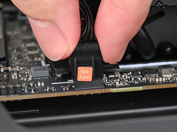 Slide the cable over the four-pronged connector labeled &quot;Sys Fan1,&quot; making sure the orange label slots between the vertical lines.