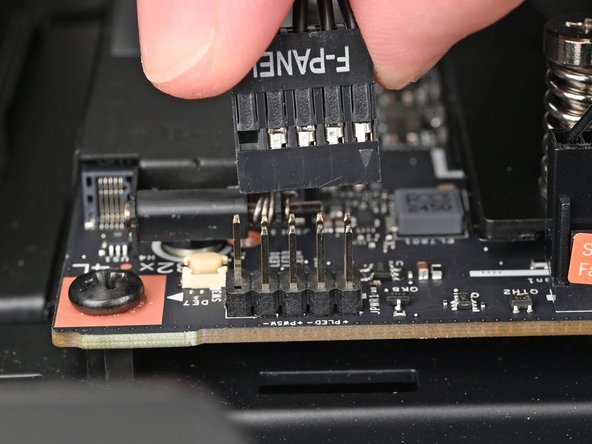 Slide the front panel header cable into its 9-pin connector underneath the primary storage.