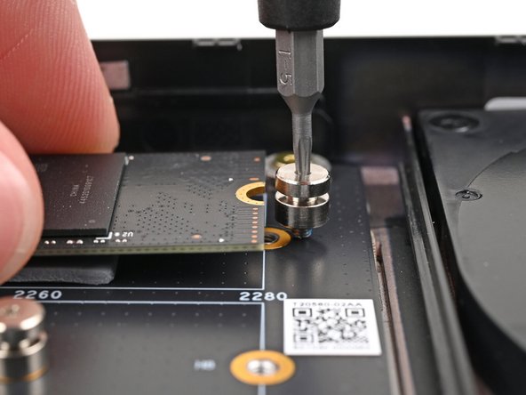 While lightly pressing the SSD into the thermal pad, guide the gap in the SSD screw into the notch on back of the SSD