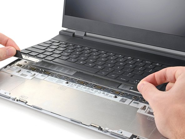 Grip the two pull tabs along the bottom of the keyboard and lift until its magnets release.