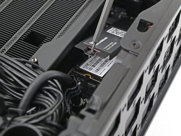 Insert your Framework Desktop Screwdriver into the captive screw on the primary storage heat spreader and press it flat to the Mainboard.