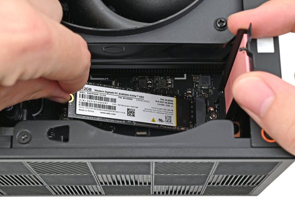 While holding the heat spreader upright, align the SSD's gold contacts with its socket.