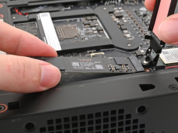 While holding the heat spreader upright, grab the SSD by its edges and pull it out of its socket.
