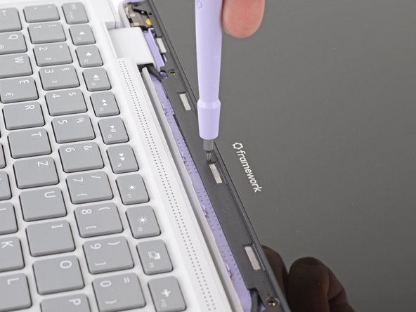 Slide the display down towards the hinge edge to release the tabs holding the top edge of the display in place.