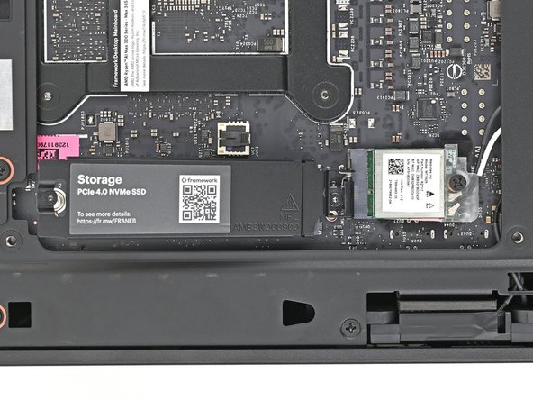 While securing the secondary storage heat spreader with one hand, use your Framework Desktop Screwdriver to remove the 4.5 mm‑long T5 Torx screw securing it.