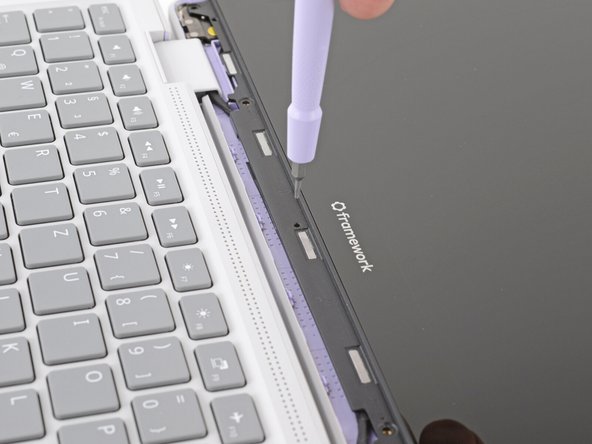 Insert the bit end of your Framework Screwdriver into the small hole on the display, below the Framework logo.