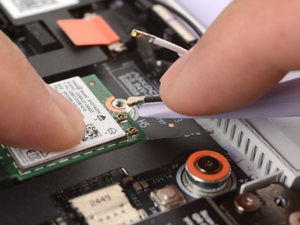 Slide the flat edge of your Framework Screwdriver under the white antenna cable, as close to the metal head as possible.