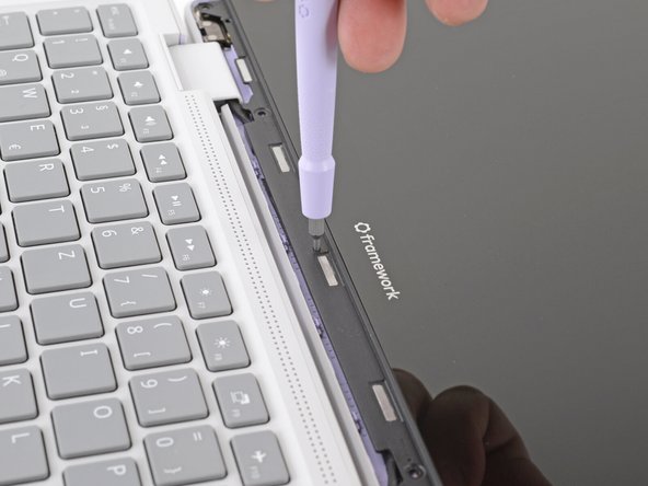 Slide the display down towards the hinge edge to release the tabs holding the top edge of the display in place.