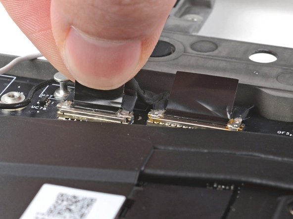 Grip the webcam cable connector to the right of the Wi-Fi module slot by its pull tab and lift up to disconnect it.