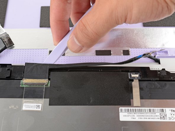 Slide the flat end of your Framework Screwdriver under the length of the display cable to separate it from the display.