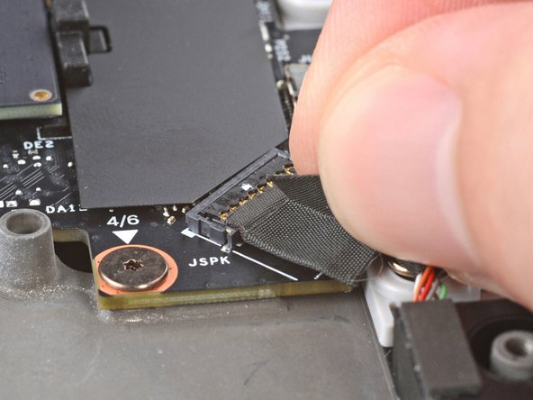 Lift the speaker cable connector by its black pull tab and disconnect it.