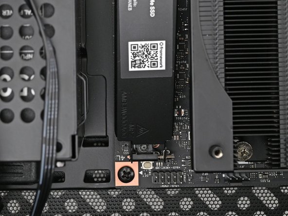 While securing the primary storage heat spreader with one hand, use your Framework Desktop Screwdriver to remove the 4.5 mm‑long T5 Torx screw securing it.