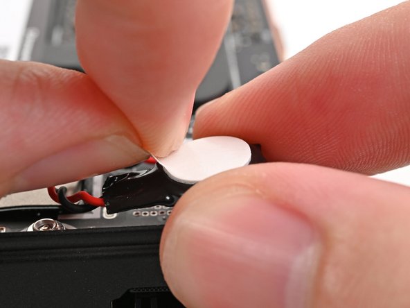 Peel the white liner off the back of the RTC battery to expose the adhesive.