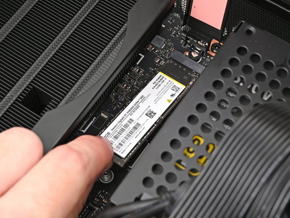 While holding the heat spreader upright, align the SSD's gold contacts with its socket.