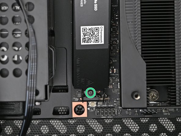 While securing the primary storage heat spreader with one hand, use your Framework Desktop Screwdriver to remove the 4.5 mm‑long T5 Torx screw securing it.