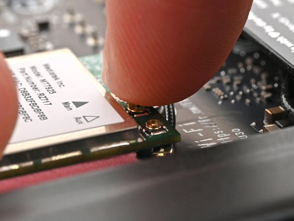 Position the black antenna cable connector over the left Wi-Fi module's coaxial socket.