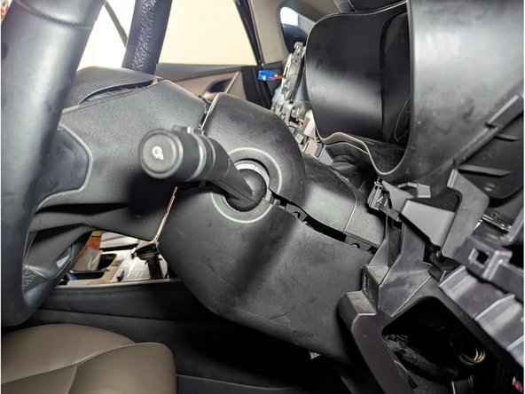 Unclip the steering column cover using a flat-bladed screwdriver or plastic pry tool.