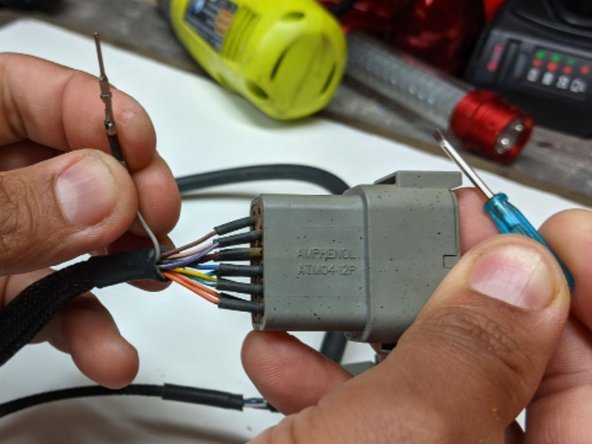 With the screwdriver provided, push down on each tab inside the Connector. This allows for the pin to unlock and slide out. Repeat this step for all the pins to completely de-pin the Connector