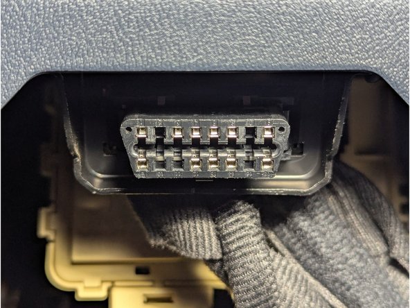Carefully unclip the vehicle's OBD-II port and detach it from the metal bracket.