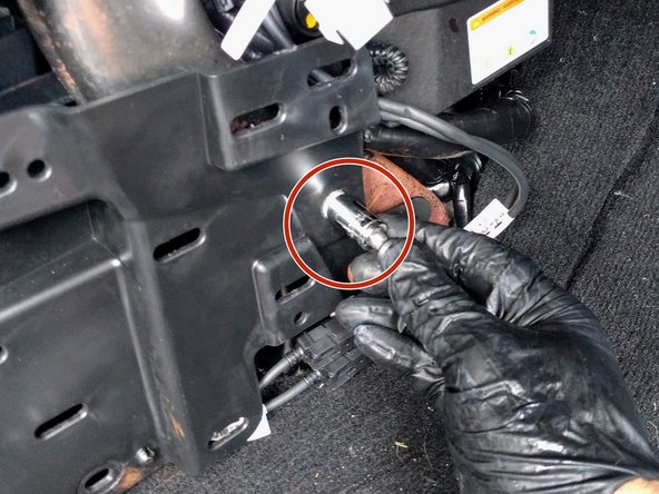 Use a ratchet with a 13mm socket to remove the bolt from the plastic panel as shown in the image.