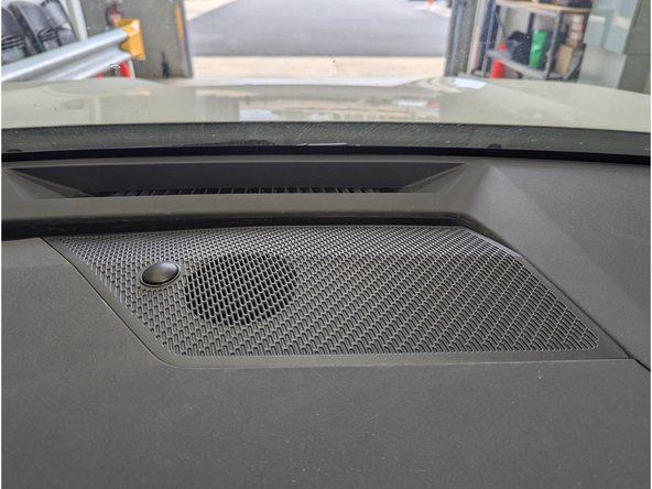 Using a plastic panel removal tool, detach the center channel speaker grille which is held by plastic fasteners.