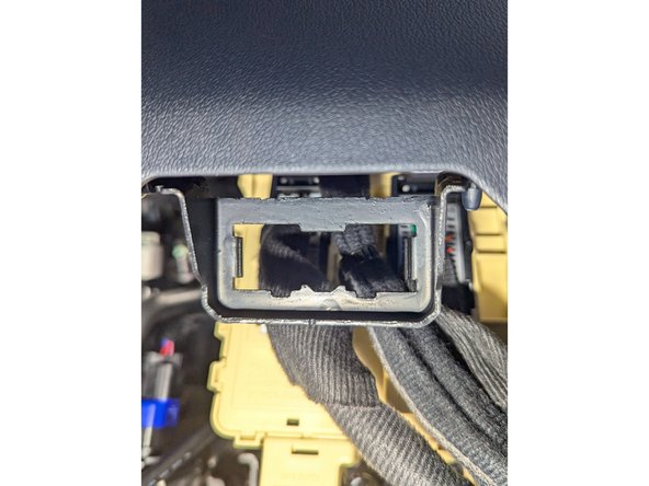 Carefully unclip the vehicle's OBD-II port and detach it from the metal bracket.